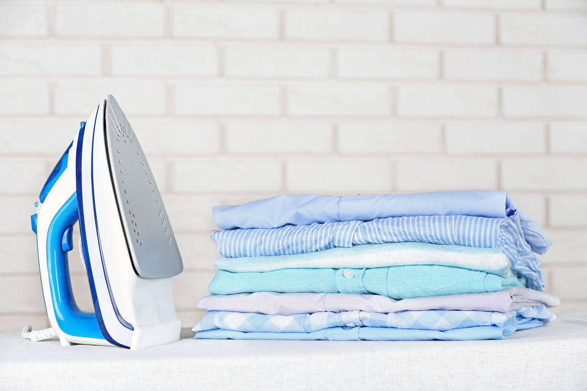 Electronic Iron and Pile of Clothes with Brick Wall Background